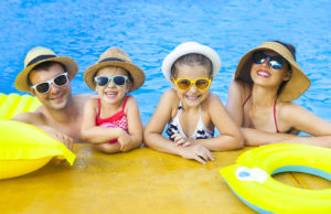 Happy family with two kids having fun in swimming pool